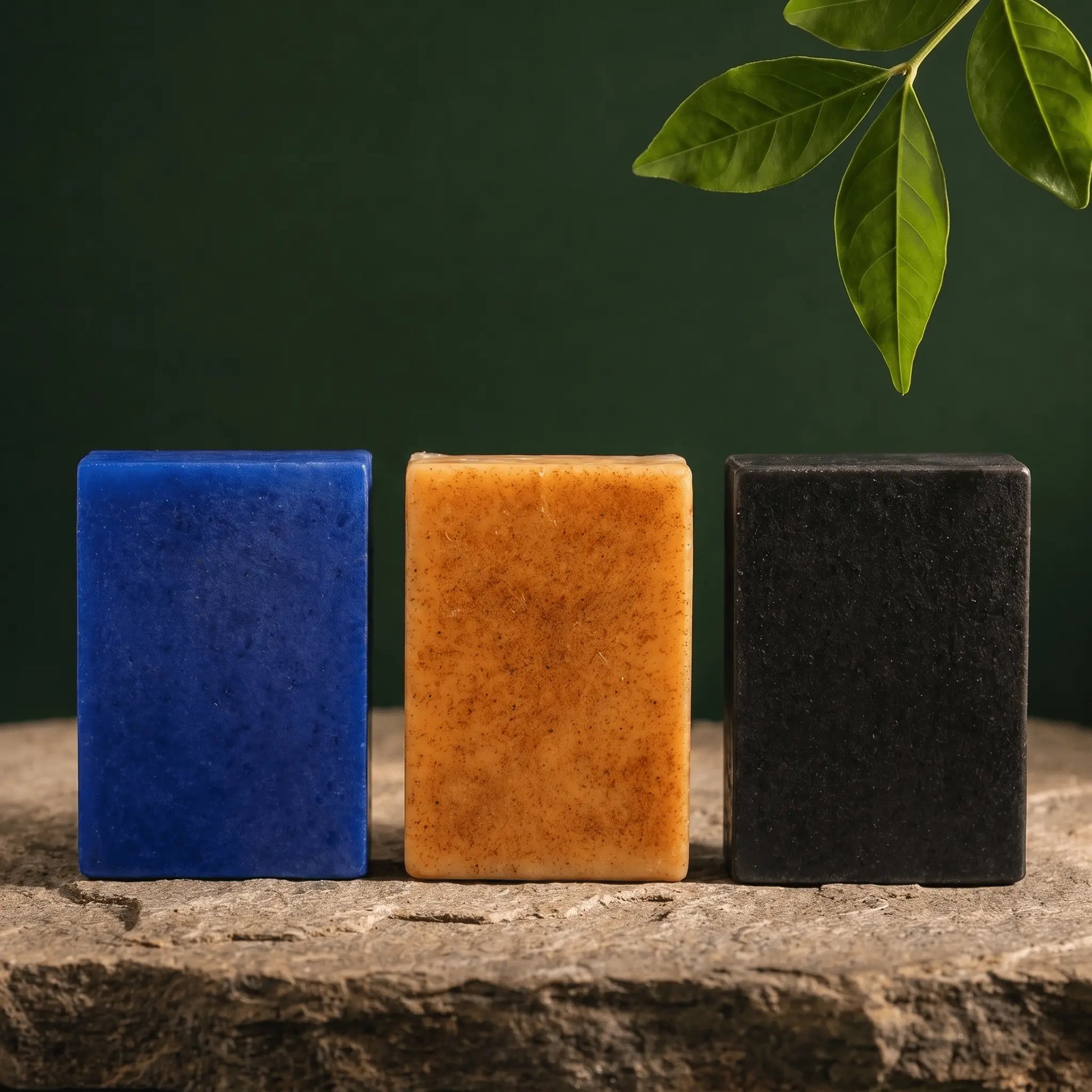 Premium Skincare Trio soap bundle by Urban Tree Pakistan featuring Moroccan Nila, Turmeric Kojic Acid, and Charcoal Activated soap bars 100g in a front-facing row on natural stone with botanical dark green background