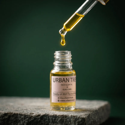 Close-up of Urban Tree Glass Skin Elixir golden face oil dropping from a glass pipette into the bottle