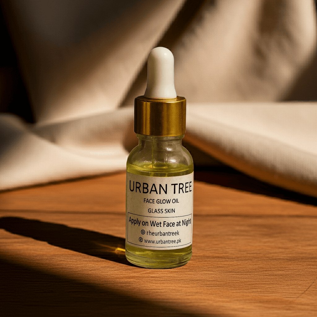 Urban Tree Face Glow Oil Glass Skin hydrating serum bottle on wooden surface with soft neutral fabric background – organic natural skincare in Pakistan