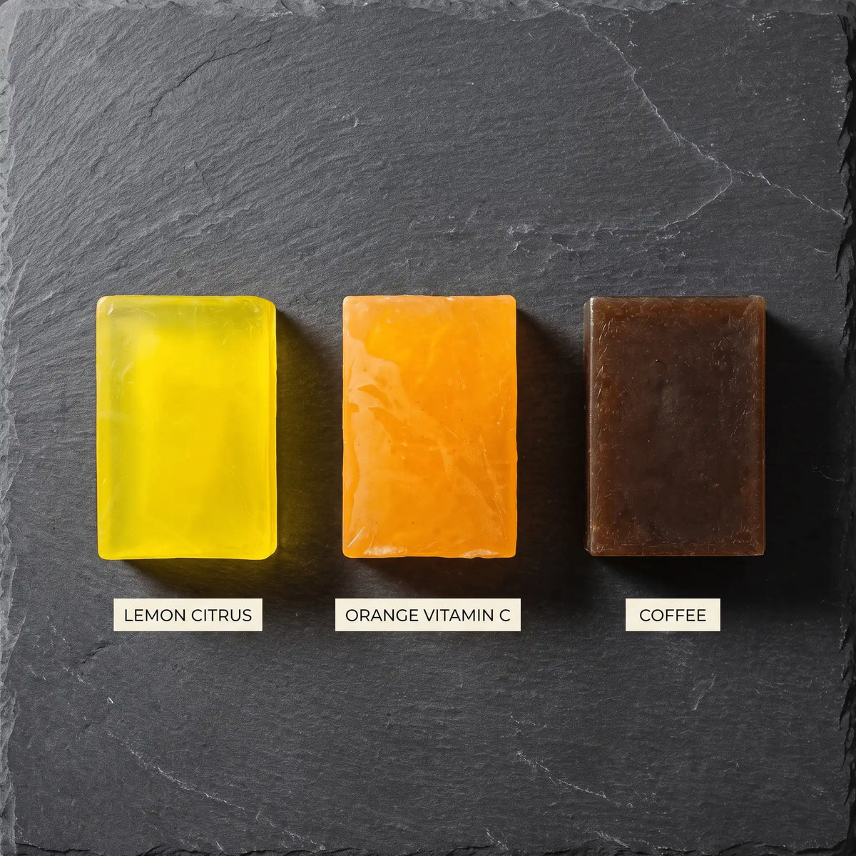 Overhead view of three Urban Tree soaps on dark slate, labelled Lemon Citrus, Orange Vitamin C and Coffee