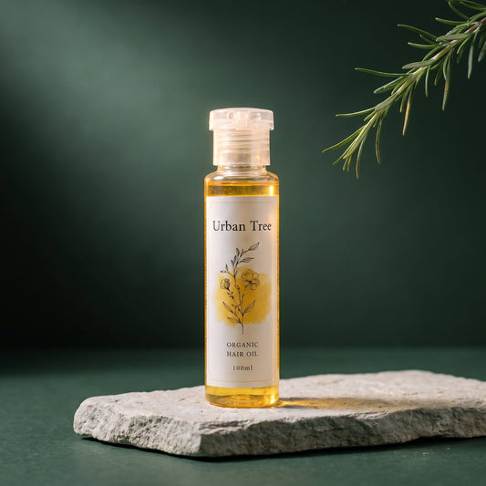 Urban Tree Organic Hair Oil 100ml bottle of golden herbal oil on a stone slab against a deep green background